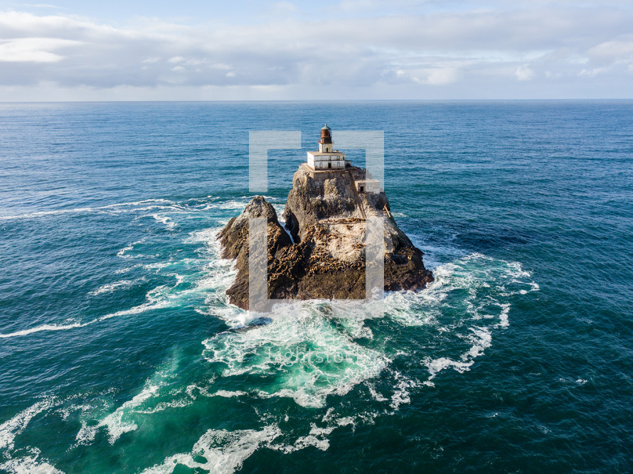 lighthouse on a rock island surrounded by the ocean 