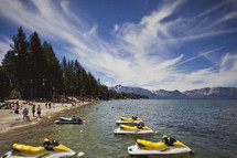A beach with yellow jet skis tied in the water