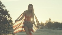 Young Woman Wrapped in American Flag Walks Toward Camera in Slow Motion