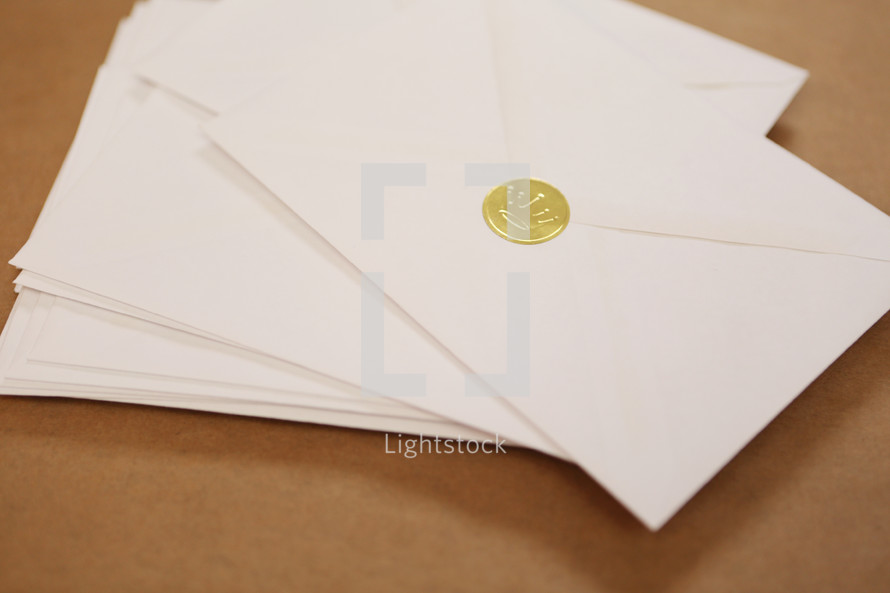 A stack of Christmas cards in envelopes with gold crown seal.