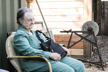 An elderly woman sitting in a chair holding her purse 