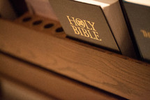 Holy Bible and hymnal in the back of a church pew.