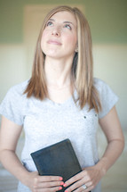 Woman holding a Bible looking up to God.