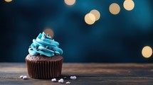 Cupcake with blue icing on wooden table and bokeh background