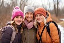 Three women with backpacks looking at camera in a park in winter