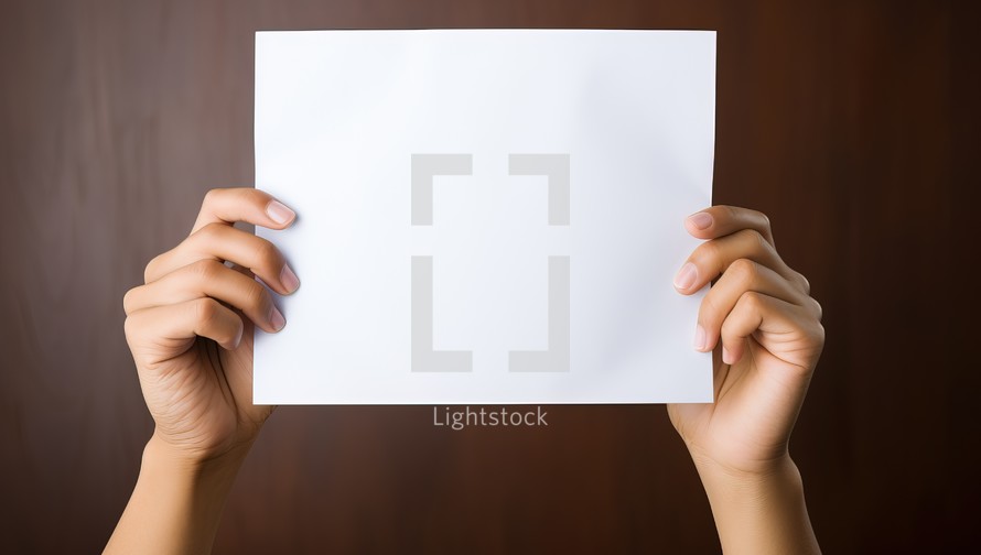 Hands holding a blank paper sheet with copy space on brown background