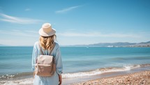 Back view of young woman in hat looking at sea on a sunny day