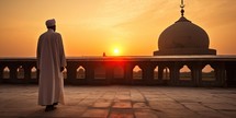 a Muslim man at sunset in front of mosque