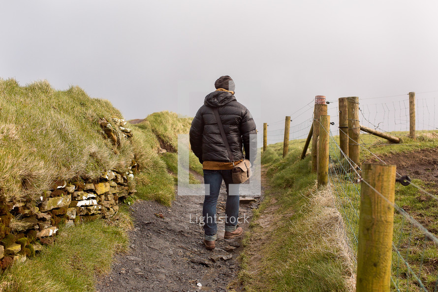 man hiking on a path on the cliffs of moher 