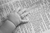 Infant hands laying on a bible