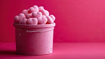Pink heart shaped marshmallows in a pink bucket on a pink background