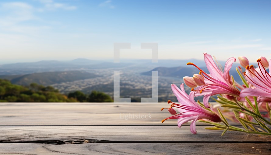 Pink lily flowers on wooden table with mountains and blue sky background