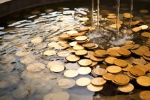 gold coins falling into a water fountain with bokeh background.