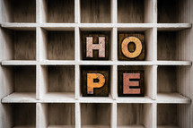Wooden letters spelling "hope" on a wooden shelf.