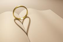 wedding band forming a heart shadow between the pages of a book 