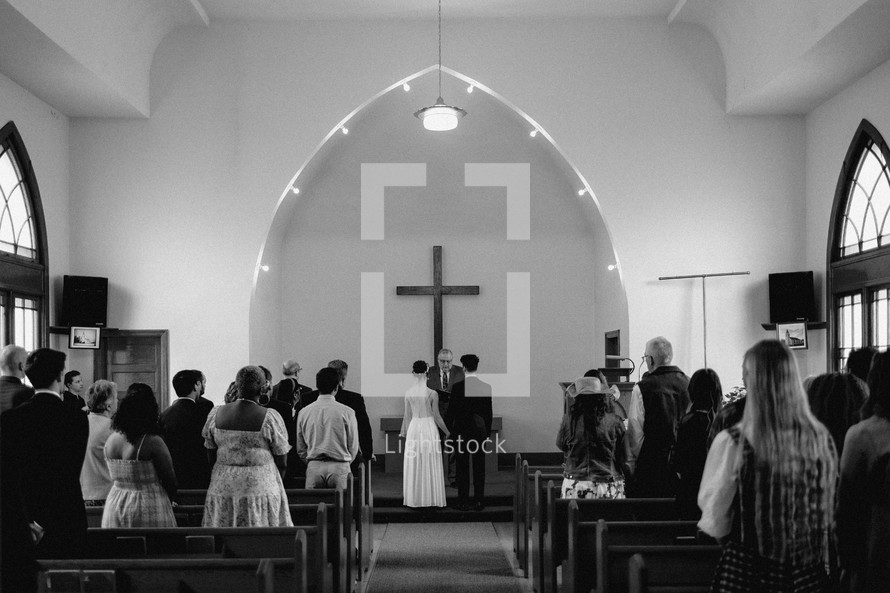 Black and white photo of a wedding ceremony inside small church.