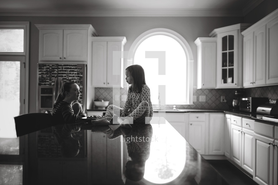 sisters sitting on a kitchen counter 
