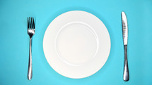 Table setting in restaurant or cafe. Fork and knife. White plate on blue table. High quality photo