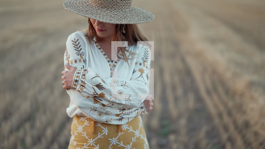 Portrait of ukrainian woman in wheat field after harvesting. Attractive cheerful lady in embroidery vyshyvanka blouse and straw hat. Ukraine, independence, freedom, patriot symbol, charming girl