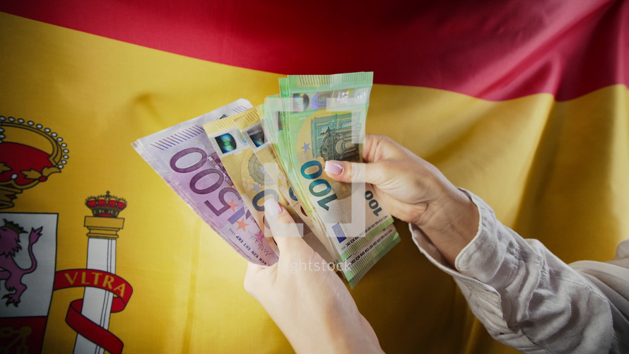 Spanish flag background. Woman counting euros. 