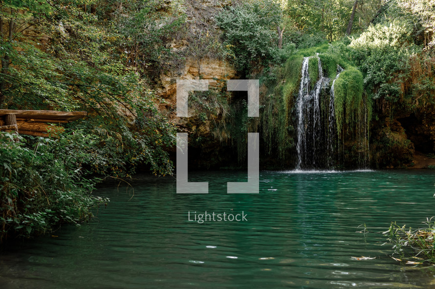 Long exposure waterfall during the day. green forest and rocky mountain. summer time. crystal clear blue water. beautiful waterfall with blue lake in the forest