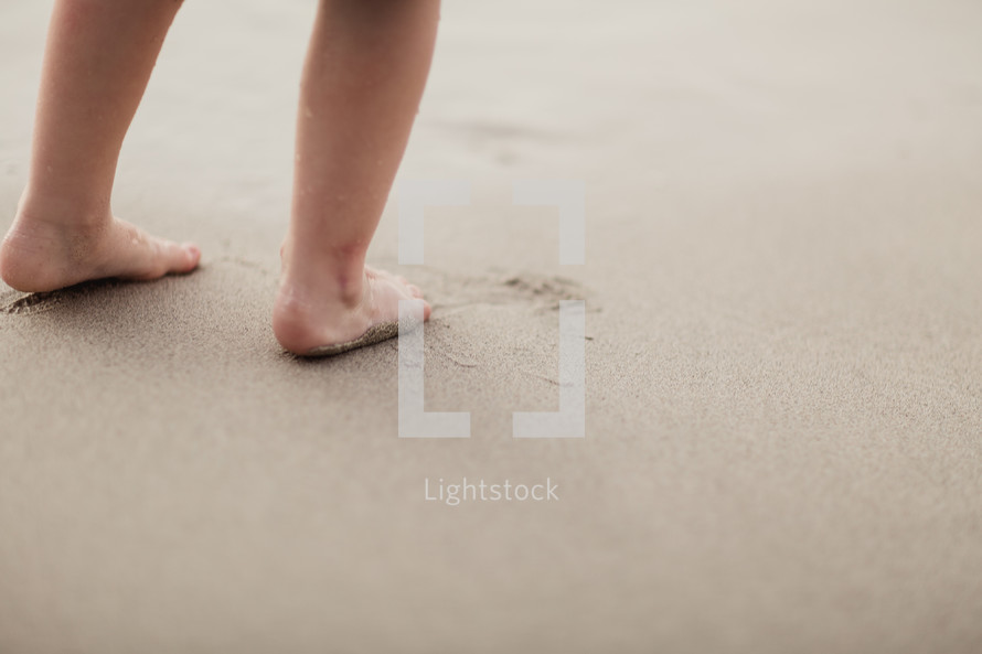 toddler's feet on a sandy beach 