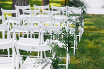 decorated white chairs at a wedding ceremony.