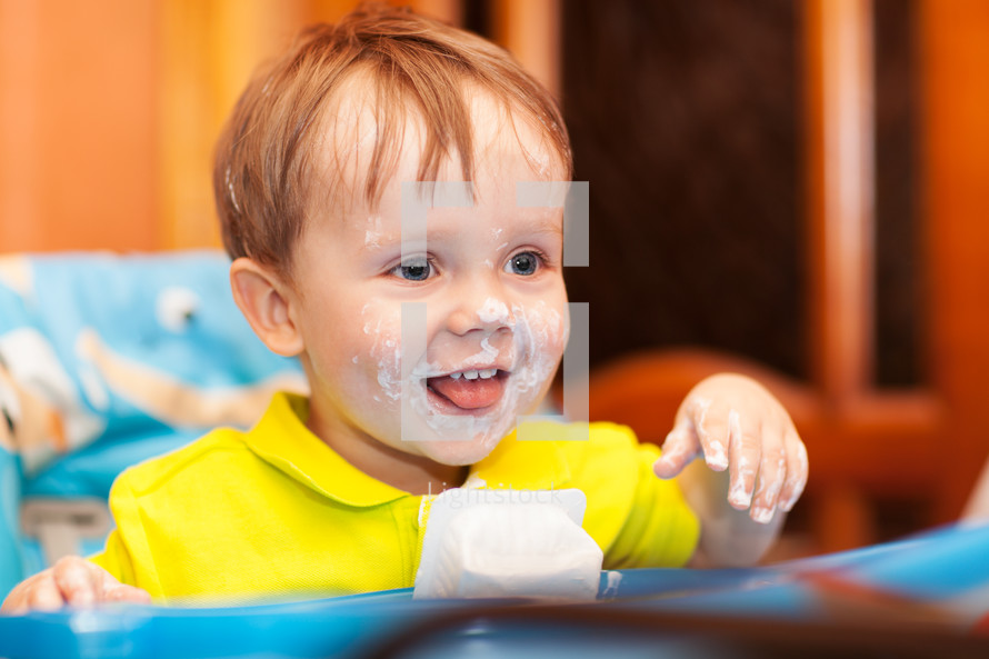 Happy child dirty with cream yogurt