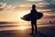 a man with a surfboard at sunset 