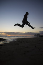 silhouette of a man leaping on a beach 