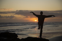 man with crane pose on a beach at sunset 