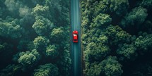 Aerial view of red car driving on the road in the forest