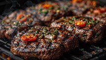Grilled beef steaks with chili peppers and herbs on the grill