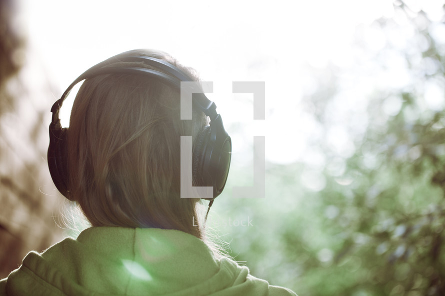Woman in headphones against bright sunlight