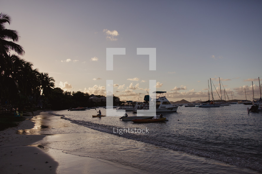 anchored boats and tide washing onto a shore at sunset 