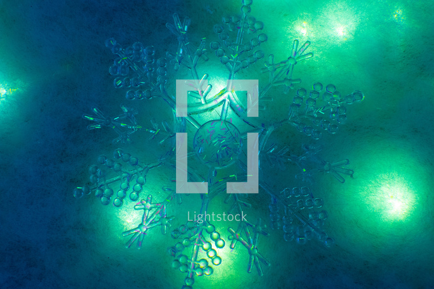Clear snowflake on blue background with lights