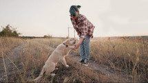 Training of little golden retriever puppy. Woman with dog on nature backdrop. Happy lovely pet playing, new member of family. Doggy training. High quality 