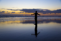 silhouette of a man with open arms standing on a beach 