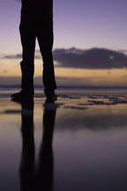 legs standing on wet sand 