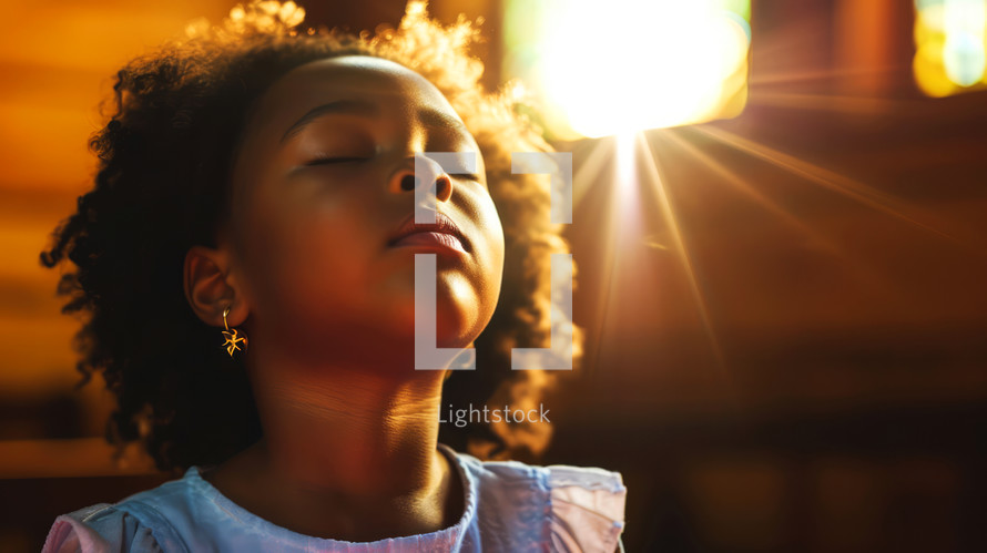 Portrait of beautiful african american girl with closed eyes in the sunlight, praying.