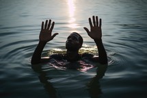 Baptism. Silhouette of a young black man in worship in the water at sunset