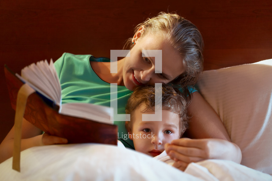 Young mother reading to her child in bed