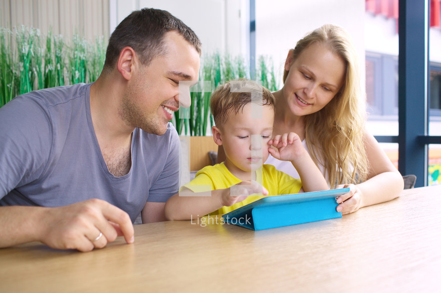 Happy family of three with tablet computer in cafe