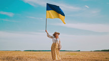 Ukrainian woman waving national flag in wheat field after harvesting. Charming rural lady in embroidery vyshyvanka. Ukraine, independence, freedom, patriot symbol, VICTORY, win in war.
