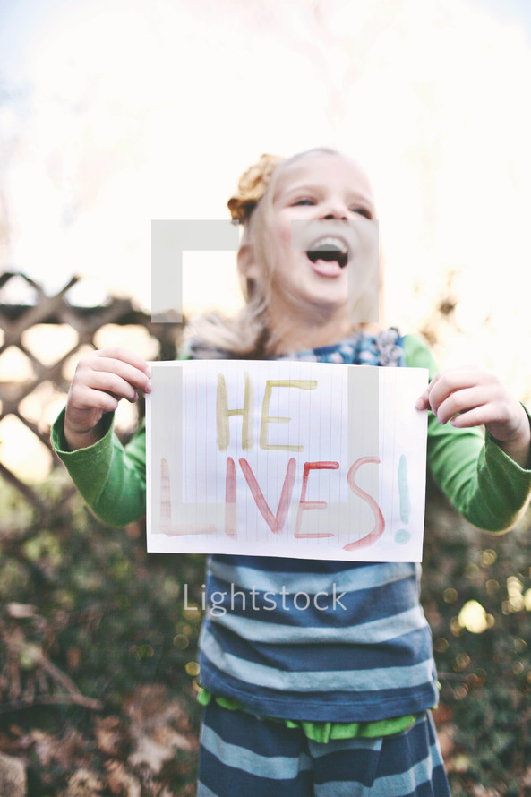 girl holding a sign that says "He lives"