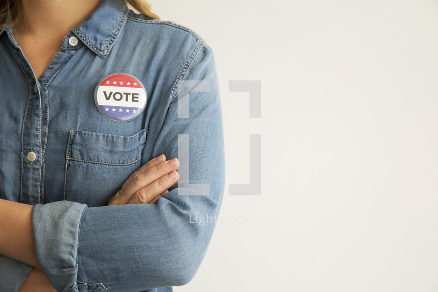 A woman in a denim shirt wearing a red, white and blue button reading, "Vote."