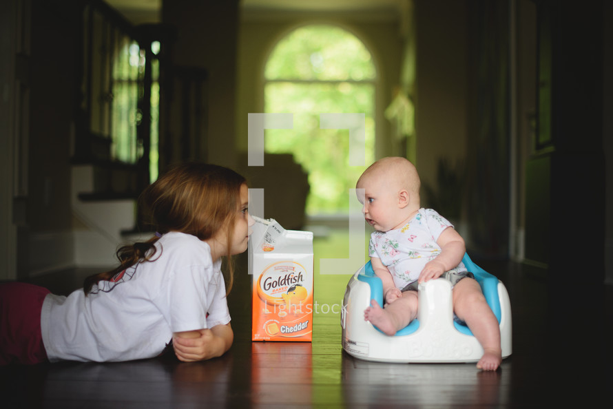 siblings on a wood floor with goldfish 
