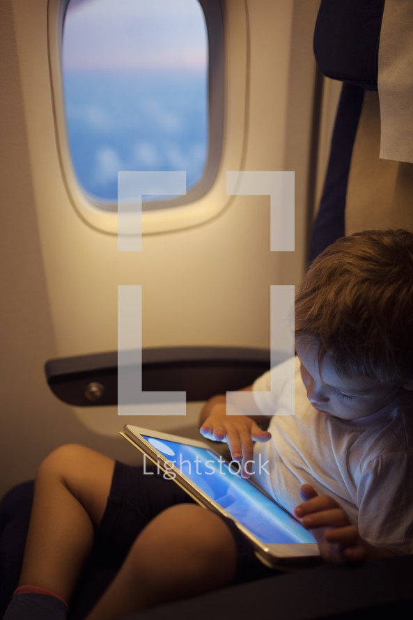 Boy spending time with tablet PC during flight