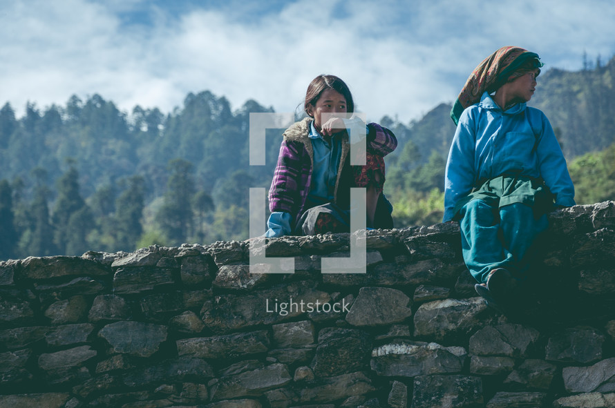 children sitting on a stone wall 