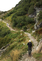 man hiking on a path up a mountain 